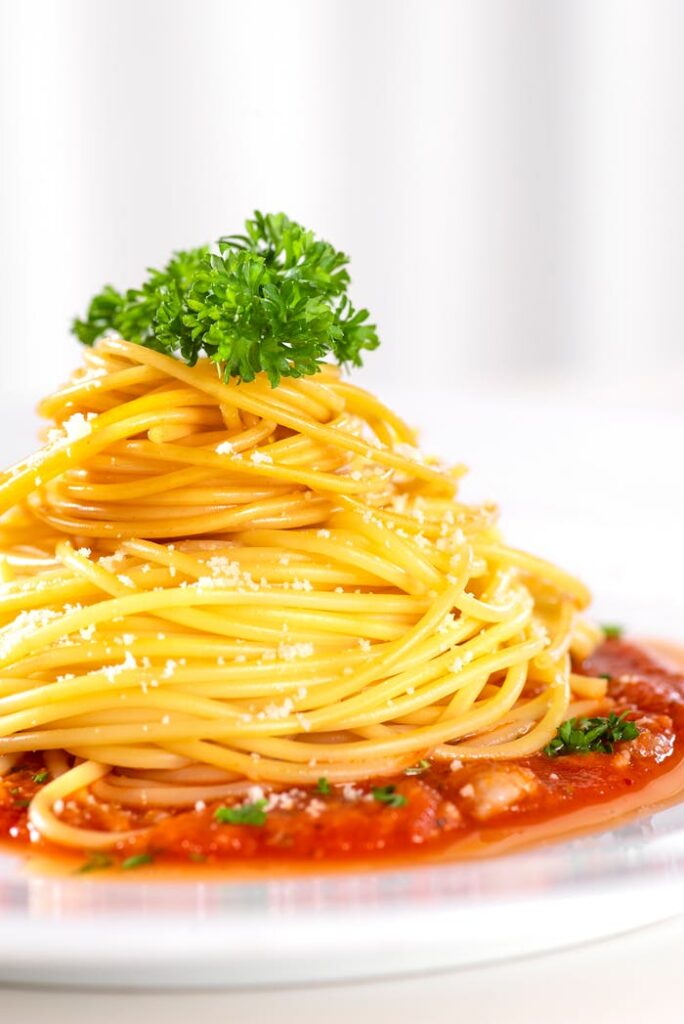 pexels-photo-18904796 Close-up of spaghetti with tomato sauce, garnished with herbs and cheese.